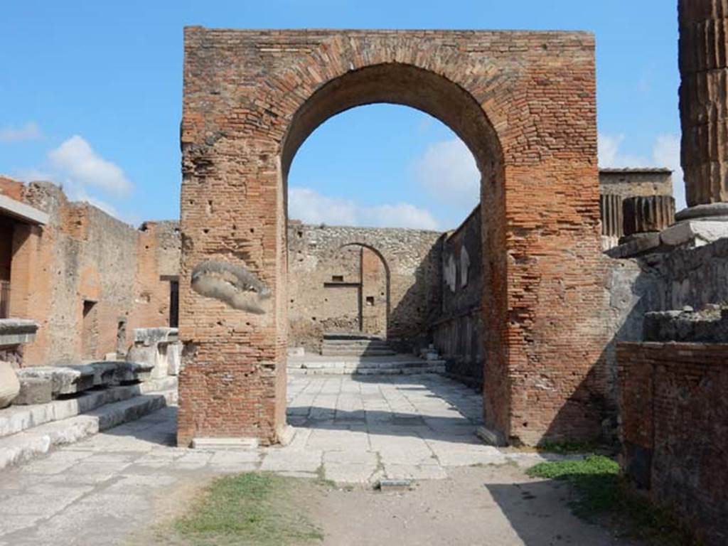 Arched entrance in north-west corner of Pompeii Forum, May 2015. Looking north through the Arch of Augustus to the arched entrance with its steps. Photo courtesy of Buzz Ferebee.
On ADS 1210a the arch is referred to as the Arco di Caio e Lucio Cesare.
Caius/Gaius Julius Caesar and Lucius Julius Caesar were sons of Marcus Vipsanius Agrippa and Giulia the Elder, daughter of Augustus. 
They were part of the imperial family of Augustus, known as the Julio-Claudian dynasty. 
The year of their father's death (12 BC), their maternal grandfather, Augustus adopted them and named them as his heirs. 
They grew up and were educated by their grandparents but did not succeed Augustus as they died before him, in 4 AD and 2 AD respectively.
