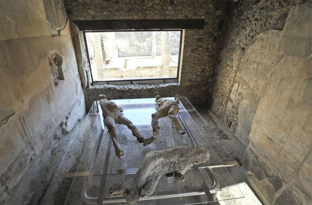 VII.1.47 Pompeii. March 2017. Room 8, looking across plaster-casts towards window in east wall.
Plaster-cast of victim 2 can be seen in the lower part of the photograph. 
The fractured remains were badly hit by the 1943 bombing of the Antiquarium.
In this photo, she is seen lying with her head to the right, whereas in the Sommer and Behles photo, above, she is lying with her head to the left.
They were found in the Vicolo degli Scheletri.

