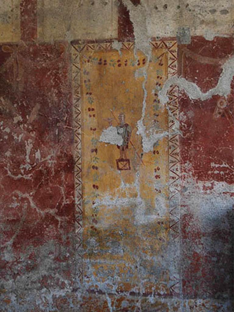I.6.12 Pompeii. October 2013. Painted decoration on south wall.
Photo courtesy of Paula Lock. 
In this room, the low zoccolo/plinth was yellow and sprinkled with red.
Above the zoccolo, in the middle zone of the south wall are the remains of two large red painted panels, with a narrow yellow panel between them.
Hanging in the red panels were painted garlands, shields, discs and lances; the vignette in the centre of the east panel depicted a dove, and the vignette in the centre of the other red panel showed a couple of doves on a branch.
In the yellow panel was a painted figure.
According to de Vos in PPM, the male figure dressed in a green tunic and red cloak, painted on a yellow background, held a decoy bird in his raised right hand and a long twig (una paniuzza) in his left hand, and was standing on a cage that served for transport and base for the decoy. 
The upper zone of the wall was painted white and divided into panels by red vertical borders.
See Carratelli, G. P., 1990-2003. Pompei: Pitture e Mosaici: Vol. 1,  Roma: Istituto della enciclopedia italiana, p. 398-9.
