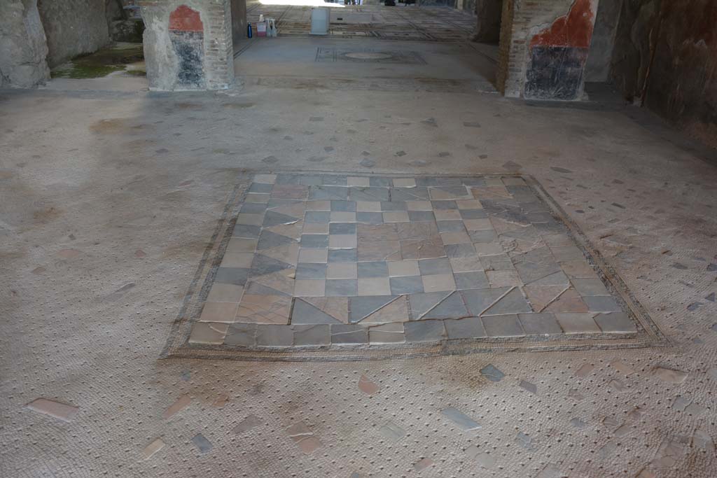 I.7.1 Pompeii. October 2019. Flooring in oecus, looking south across tablinum towards atrium.
Foto Annette Haug, ERC Grant 681269 DCOR.
In the centre of the floor of the oecus was an emblema in opus sectile of coloured marble.
This was made from square tiles with contrasting triangles and edged with a double black mosaic band.

