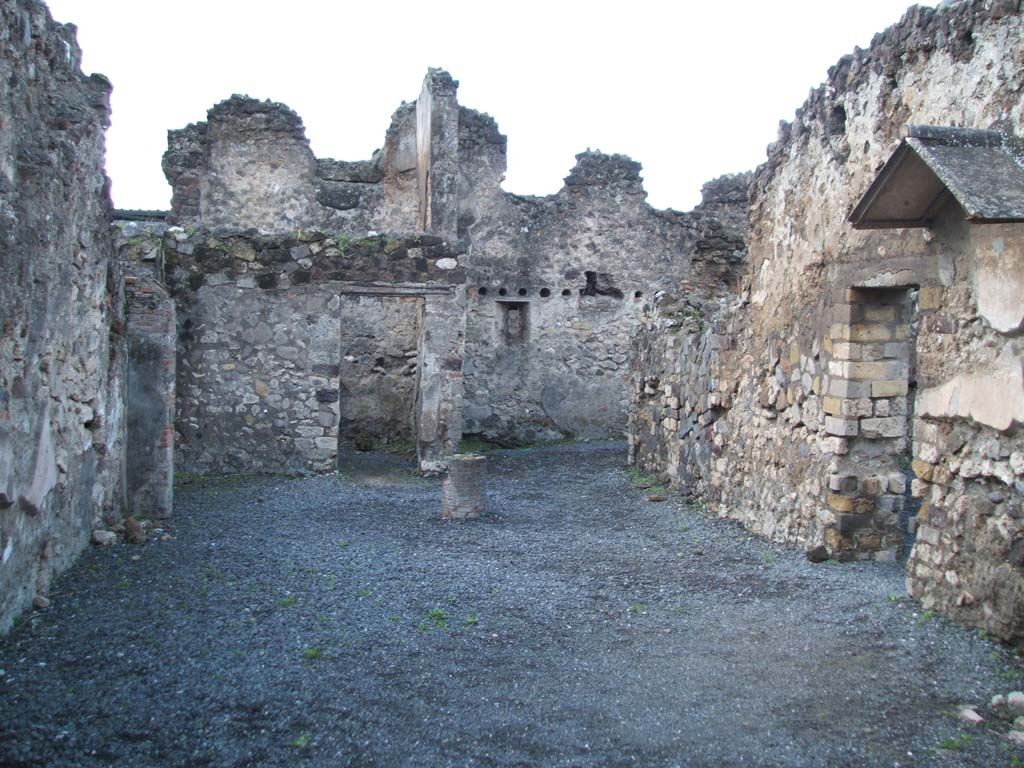 VI.4.4 Pompeii. December 2004. Looking west.
In the centre of the photo, next to the doorway in the west wall, can be seen the site of the latrine.
According to Garcia y Garcia, apart from the wear-and-tear of time, the disintegration of the sales counter was due to the bomb that fell to the south of the insula in 1943. In the hurried succeeding restoration, many elements and several structures have remained destroyed or have been forgotten.
In this hospitium, walls of the two latrines have been forgotten.
See Garcia y Garcia, L., 2006. Danni di guerra a Pompei. Rome: L’Erma di Bretschneider. (p. 75)
According to Hobson, at the rear of the property is a small room the northern wall of which is no longer standing, despite being shown on the plan.
This room has a sloping tile feature. There is a window where the latrine appears to be.
See Hobson, B. 2009. Pompeii, Latrines and Down Pipes. Oxford, Hadrian Books, (p. 202)
According to Boyce, another latrine may have been in the recess in the north-east corner of this room, near to the lararium on the north wall.
See Boyce G. K., 1937. Corpus of the Lararia of Pompeii. Rome: MAAR 14.  (p. 46, no. 151).

