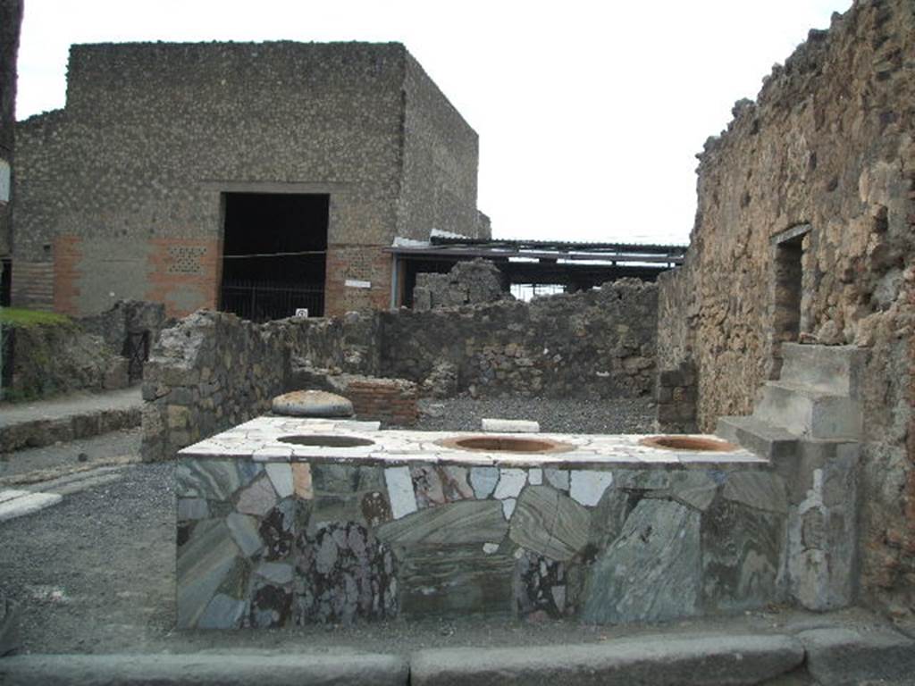 VI.4.8 Pompeii. December 2006. Sales counter, looking west to rear room. 
The entrance, VI.4.9 on Via delle Terme, can be seen on the south (left) side. According to Garcia y Garcia, this area was nearly all destroyed by the bombing in 1943. The bomb provoked the total fall of the walls, internal and external onto Via Consolare, between the north wall and on its east side.
See Garcia y Garcia, L., 2006. Danni di guerra a Pompei. Rome: LErma di Bretschneider. (p.75)
