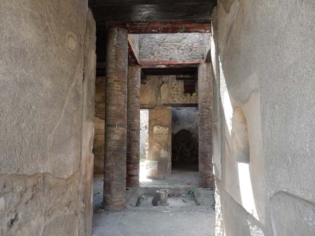 VI.15.9 Pompeii. September 2004. Entrance corridor, looking west to atrium. According to Richardson, this tiny atrium house had a very efficient design. The atrium is entered by short fauces flanked by cubicula with windows to the street. The atrium is almost square, Tetrastyle with columns of naked brick that supported a second floor.
The second floor was a gallery lit by large rectangular windows into the compluvium well. It was accessible by a small staircase against the north wall of the atrium. Although it must have made the atrium rather dark, it made living space available over the atrium, as well as over the cubicula at the front of the house. On the far side of the atrium, opened an ample triclinium and the service area. This service area in the south-west corner of the house was lit by a second light-well and had a second storey of its own, possibly just a loft for storage. NSc. 1897, 38-39, 62-64.
See Richardson, L., 1988. Pompeii: an Architectural History. Baltimore: John Hopkins University Press. (p.345-6)
(Note – the staircase is actually against the south wall of the atrium)
