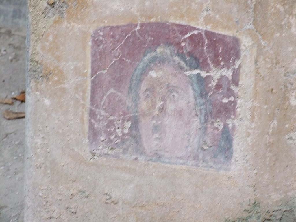 VI.16.15 Pompeii. December 2006. 
Atrium B, between doorway to room E and room D at base of wall. Detail of wall painting of face or mask.
