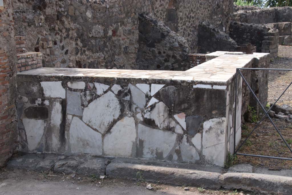 VI.17.4 Pompeii. September 2021. 
Looking west along south wall with two-sided marble counter with hearth and display shelves. Photo courtesy of Klaus Heese.
