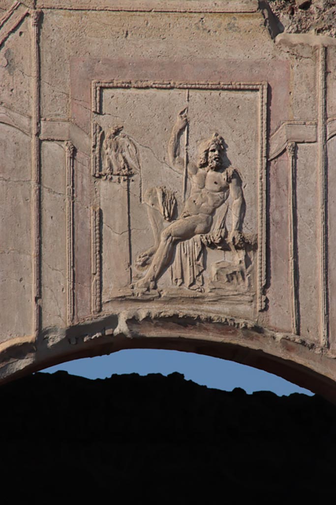 VII.1.8 Pompeii. October 2022. 
Stucco relief of a seated Zeus, above arch of nymphaeum F. Photo courtesy of Klaus Heese.
