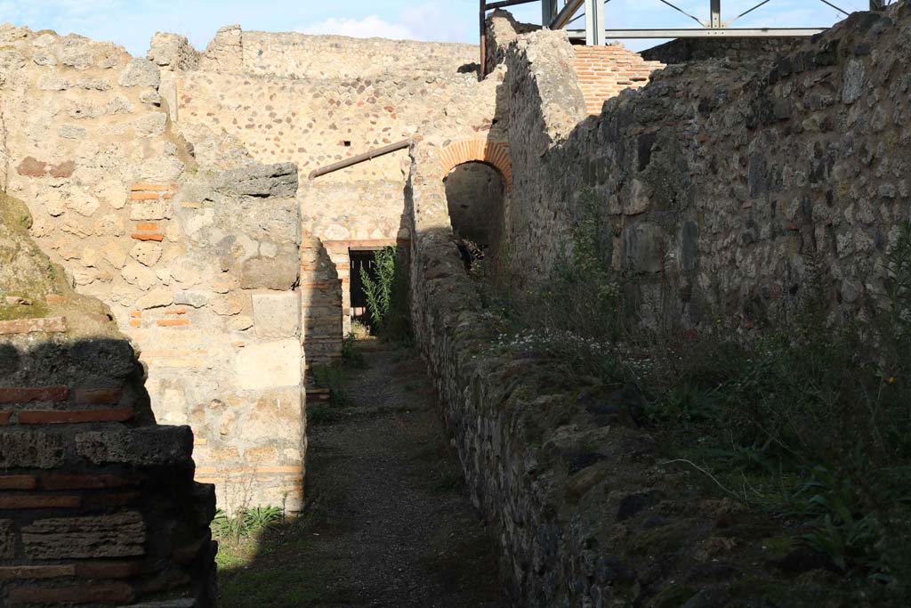 VII.1.58, Pompeii. December 2018. 
Looking north from end of entrance at VII.1.58, a corridor at rear of shops VII.1.52-VII.1.57 with Stabian Baths at rear. 
Photo courtesy of Aude Durand.
