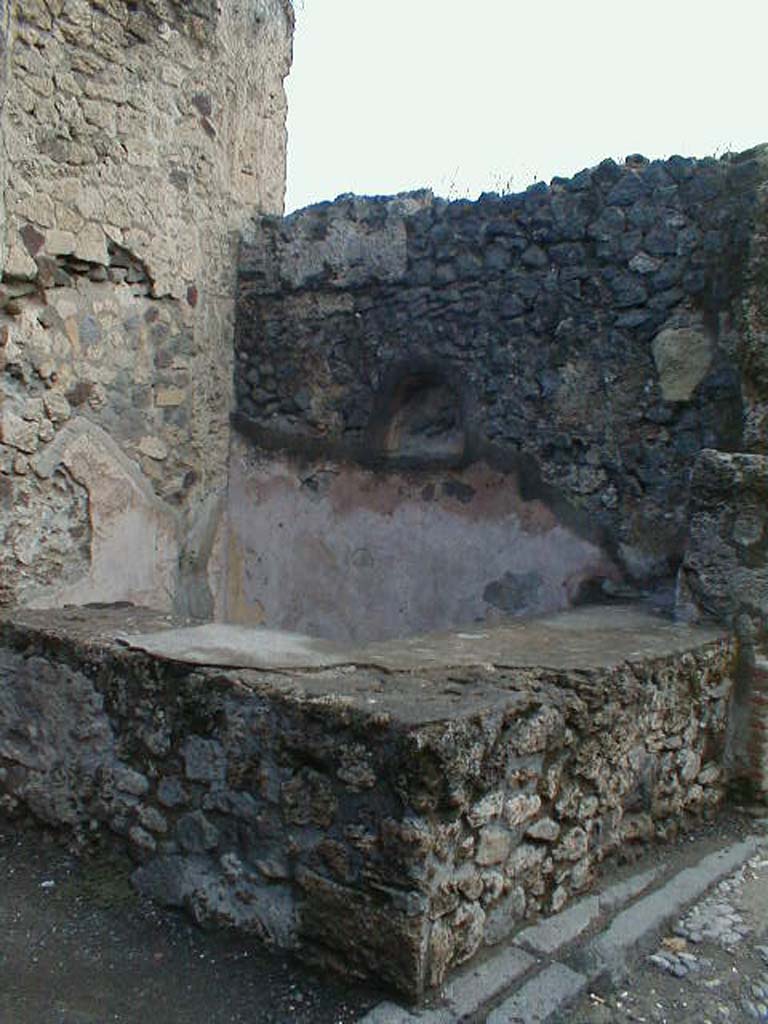 VII.7.11 Pompeii. September 2004. Two-sided sales counter, with niche for lararium in east wall. 
According to Boyce, the inside walls of the arched niche were coated with yellow stucco.
See Boyce G. K., 1937. Corpus of the Lararia of Pompeii. Rome: MAAR 14. (p.68, no.298)
