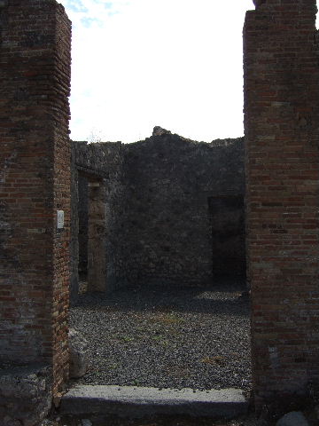 VII.7.21 Pompeii. September 2005. Looking south across atrium towards doorway to small enclosed tablinum. According to Garcia y Garcia, the bombardment caused the destruction of he walls of two rooms, with the loss of painted plaster. 
See Garcia y Garcia, L., 2006. Danni di guerra a Pompei. Rome: L’Erma di Bretschneider. (p.116)
