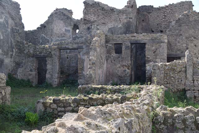 VII.10.12 Pompeii. March 2009. Looking west at floor and wall with a door with plaster in the lower area.