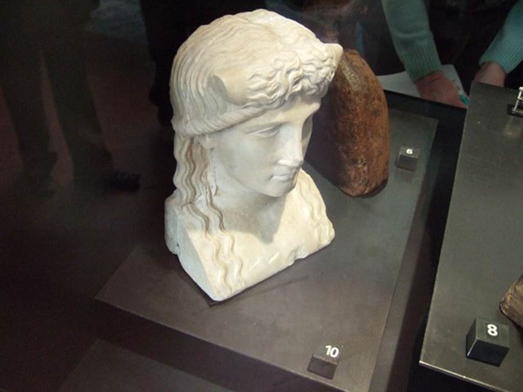 Marble statuette of Iside-Io? Found in IX.7.23, according to Naples Museum card.  
Now in Naples Archaeological Museum.  Inventory number 119584.
According to Jashemski and Dwyer, this was found in the atrium of IX.7.20, but probably belonged to the peristyle.
It was discovered on 28th October 1880, and described as –
Bust for a herm. White marble. Height m.0.21.
The back of the bust is flat and the sides show cuttings for cross-bars.
A river god, with bull’s horns protruding from above temples.
Hair parted down the middle, descends in wavy tresses to chest.
See Jashemski, W. F., 1993. The Gardens of Pompeii, Volume II: Appendices. New York: Caratzas. (p.241)
See Dwyer E., 1982. Pompeian Domestic Sculpture, Rome: Bretschneider, pp.71-78.
