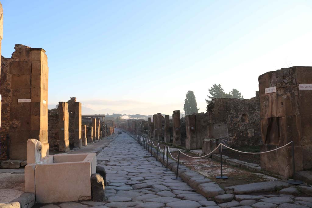 Via dell’Abbondanza, Pompeii. December 2018. 
Looking east between VII.13, on left behind fountain, and VIII.5, on right. Photo courtesy of Aude Durand.
