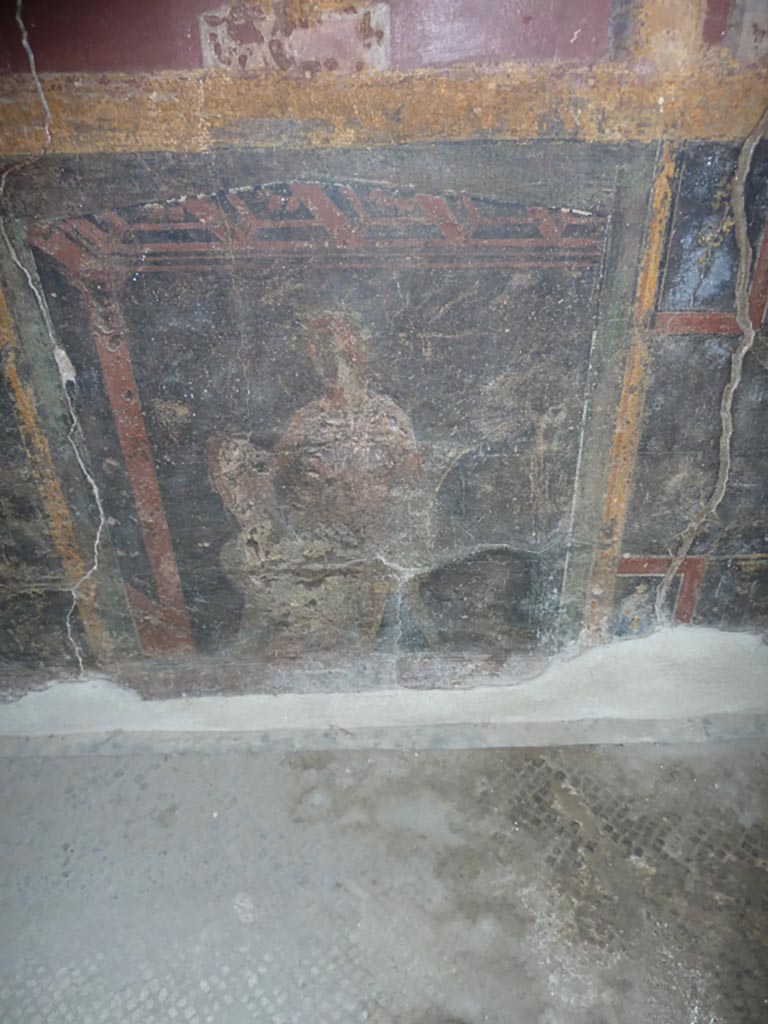 Stabiae, Villa Arianna, September 2015. 
Room 5, painted seated figure on panel in black zoccolo from east wall.
