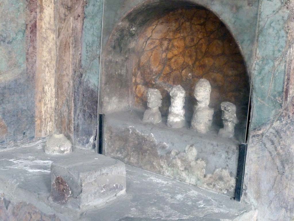 I.10.4 Pompeii. May 2010.
Alcove 25, lararium or domestic shrine. The busts are plaster cast taken from the cavities left by the original wooden busts.