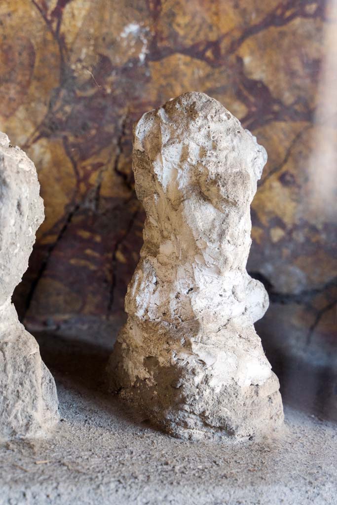 I.10.4 Pompeii. April 2022.
Alcove 25, detail of plaster cast, seen on the left of centre, on the lararium or domestic shrine. (Image 1).
Photo courtesy of Johannes Eber.
