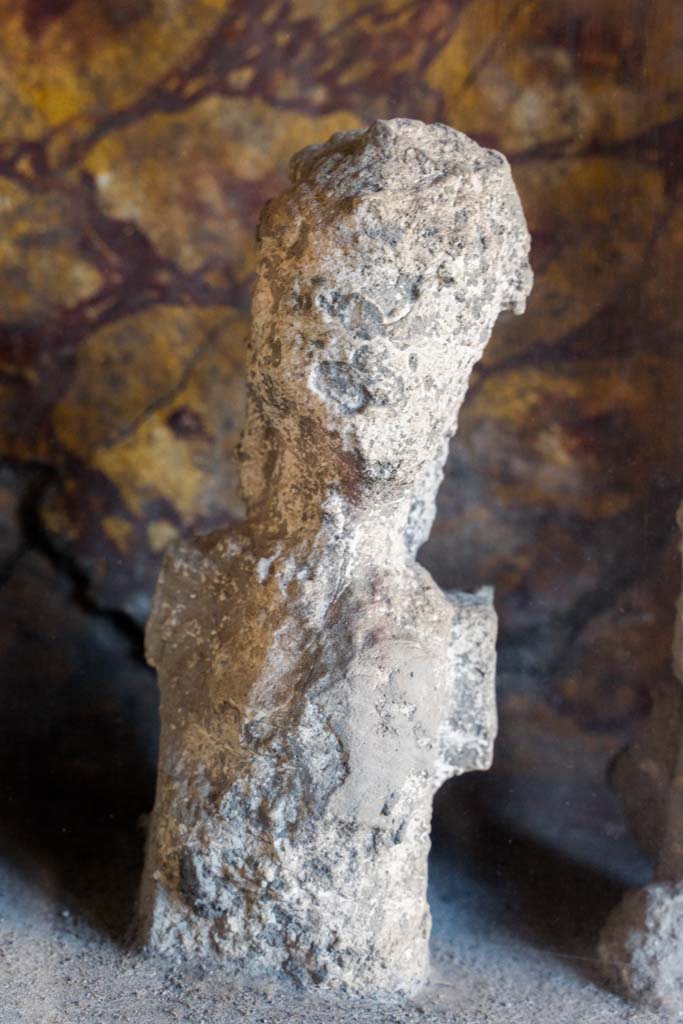 I.10.4 Pompeii. April 2022.
Alcove 25, detail of plaster cast, seen on the right of centre, on the lararium or domestic shrine. (Image 1).
Photo courtesy of Johannes Eber.