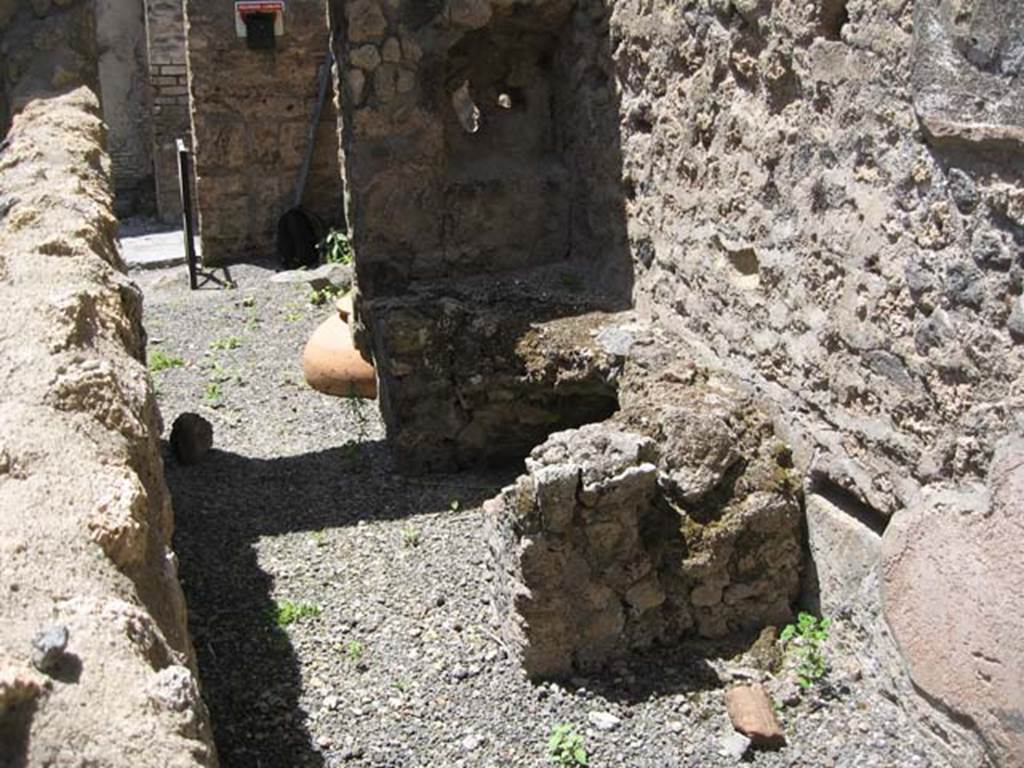VI.14.36 Pompeii. May 2013. Looking west across kitchen with hearth in north-west corner, through doorwayinto main bar-room. Photo courtesy of Paula Lock.
According to Packer, in this room the decoration originally consisted of a high yellow dado which set off walls of plain white stucco. See Packer, J: Inns of Pompeii; a short survey (in Cronache Pompeiane, IV, 1978, pages 33-37).