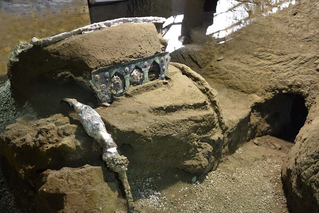 Cività Giuliana. February 2021. The four-wheeled processional chariot which has emerged intact from the excavation of the suburban villa of Cività Giuliana.
A large ceremonial chariot with four wheels, along with its iron components, beautiful bronze and tin decorations, mineralised wood remains and imprints of organic materials (from the ropes to the remains of floral decoration), has been discovered almost intact in the portico facing the stable where, in 2018, the remains of 3 equidae, including a horse still in its harness, had already been found.

This is an exceptional discovery, not only because it adds an additional element to the history of this dwelling and the story of the last moments in the lives of those who lived in it, as well as more generally to our understanding of the ancient world, but above all because it represents a unique find - which has no parallel in Italy thus far - in an excellent state of preservation.

Cività Giuliana. Febbraio 2021.  Il Carro da parata a quattro ruote emerso integro dallo scavo della villa suburbana in località Civita Giuliana.
Un grande carro cerimoniale a quattro ruote, con i suoi elementi in ferro, le bellissime decorazioni in bronzo e stagno, i resti lignei mineralizzati, le impronte degli elementi organici (dalle corde a resti di decorazioni vegetali), è stato rinvenuto quasi integro nel porticato antistante alla stalla dove già nel 2018 erano emersi i resti di 3 equidi, tra cui un cavallo bardato.

Un ritrovamento eccezionale, non solo perché aggiunge un elemento in più alla storia di questa dimora, al racconto degli ultimi istanti di vita di chi abitava la villa, e più in generale alla conoscenza del mondo antico, ma soprattutto perché restituisce un reperto unico - mai finora rinvenuto in Italia – in ottimo stato di conservazione.

Photograph © Parco Archeologico di Pompei.
