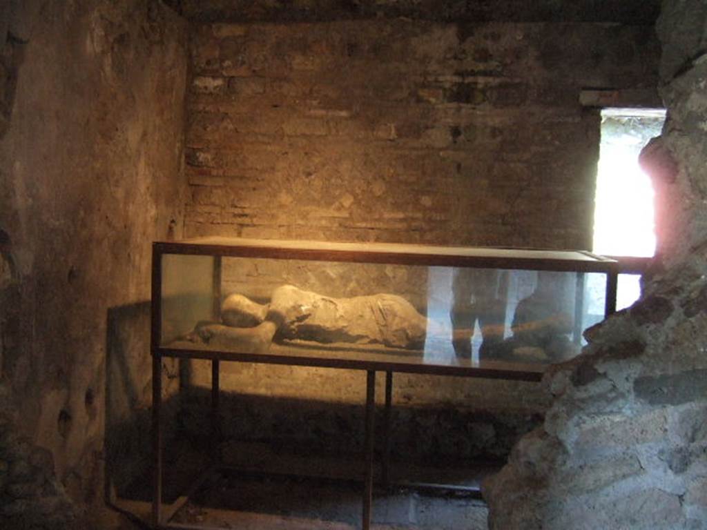 Villa of Mysteries, Pompeii. May 2006. Victim 25. Room 35, from room 34.
As the ostiarius, he had taken refuge in his closed room to die on his own bed, sheltered from the roaring storm raging outside.
He had stretched out, desperately lonely, on that poor bed, and had remained lying on his right side, his arms raised to rest his head on them as if to hide the terrible contraction of his mouth and jaws in the last breath of asphyxia. 
Come l'ostiario, in consegna, si era rifugiato nel suo chiuso stanzino per morire sul proprio giaciglio, al riparo della scrosciante tempesta che infuriava al di fuori.
Si era disteso, disperatamente solo, su quel povero giaciglio, e vi era rimasto coricato sul fianco destro, le braccia portate in alto per appoggiarvi il capo quasi a nascondere la spaventosa contrazione della bocca e delle mascelle nell'ultimo anelito dell'asfissia.
See/Vedi Maiuri A., 1967. La Villa dei Misteri. Istituto poligrafico dello stato/libreria dello stato, p.10.
