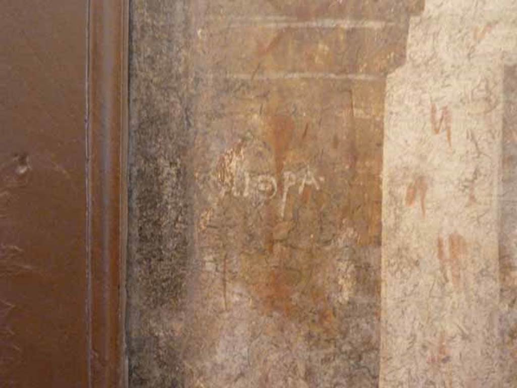 I.2.6 Pompeii.  May 2010. Detail from the wall painting of the Theft of the Palladium (Ratto del Palladio) found on the south wall of the triclinium. Name on column base.  Now in Naples Archaeology Museum, inventory number: 109751
