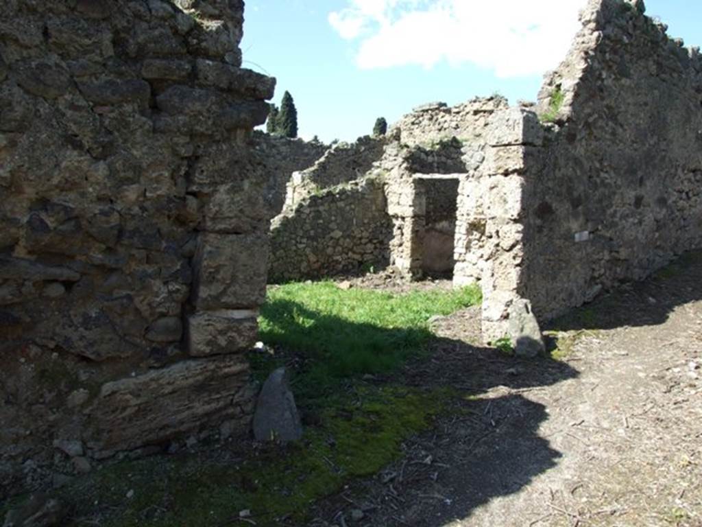 I.2.22 Pompeii. March 2009. Entrance, looking north-west. According to Warscher, quoting Mau in Bull. Inst. 1874, p.263, she described – I.2.22 “Le case che verso E danno sul vico di Tesmo, non meritano una descrizione dettagliata. Rilevo soltanto che nella prima casa verso S a destra d’uno stretto corridoio si trova prima un bacino murato rotundo (diam. 0,50 – 0,58), poi un altro quadrangolare (I,82 + 0,70), che tocca quel primo col lato corto.  Ambedue sono profondi 0,82 e congiunti presso al fondo da un foro; dal secondo l’acqua scolava verso S. In fondo al sudetto corridoio vi è la cucina, col focolare a destra fra cui e quei bacini il muro è perforato da una piccola finestra.
In una camera della stessa casa leggiamo nel pavimento in pietruzze bianche la parola “HAVE”.
See Warscher T., 1935. Codex Topographicus Pompeianus: Regio I.2. Rome: DAIR.
(translation: I. 2.22 "The house that overlooked the vico di Tesmo to the east, doesn’t deserve a detailed description.  I note only that in the first house towards the south, to the right of a narrow corridor, one found first a walled round basin (diam. 0,50 – 0,58), then another quadrangular (1,82 + 0,70), which touched against the first with its short side. Both were 0,82 deep, and joined towards the back by a hole; from the second the water drained off towards the south.  At the bottom of the same corridor there was the kitchen, with stove on the right, between which and some basins, the wall was pierced by a small window.  In a room of the same house we read the word “HAVE” written in white stones on the floor.”) 
