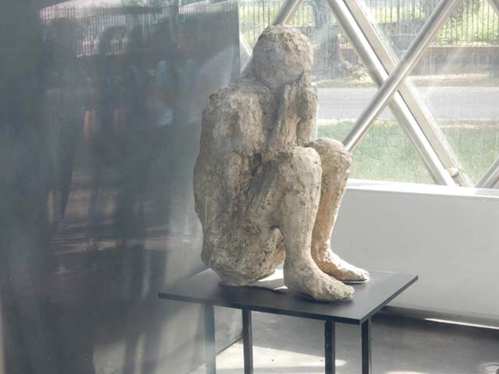 II.7.1 Pompeii. May 2018. 
Plaster cast of victim found near the latrine of the Palaestra, perhaps, as portrayed here, found crouching on the ground with his back against the wall of the east portico. Photo courtesy of Buzz Ferebee.
However, when this body was cast, he was found to be tipped forwards, huddled up and bent double on his knees, when restored he was placed in this position. 
See Stefani, G. (2010). The Casts, exhibition at Boscoreale Antiquarium, 2010. (p.10).
