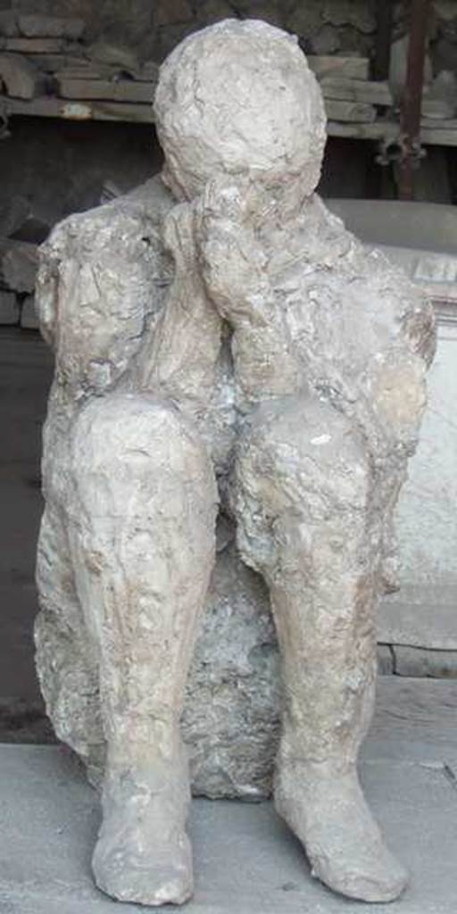 II.7.11 Pompeii. Palaestra. Plaster cast of victim found near the latrine, perhaps found crouching on the ground with his back against the wall of the east portico. Now in VII.7.29 Forum granary market.
