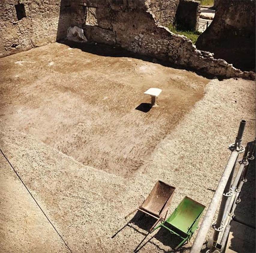 V.3 Pompeii. Casa del Giardino. May 2018. Garden. In the centre of the garden is a fluted pillar with a large piece of marble slab on top.
At a higher level, there is a large open space, probably a garden, with some amphorae still in situ (at the time of discovery). 
At the centre of the garden emerged a fluted pillar, with a large piece of marble slab, the pillar probably originally supported a stone basin (labrum) but was later reused as a support for a tabletop.
Some tree roots have been brought into evidence through the plaster cast technique. 
The garden is bordered to the east by the Casa della Soffitta, to the west by the street recently named the Vicolo dei Balconi (street of the balconies), while to the north is bordered by a Portico with at least three columns and, on the back, some pillars, with traces of fresco.

A un livello superiore, c'è un grande spazio aperto, probabilmente un giardino, con alcune anfore ancora in situ (al momento della scoperta).
Al centro del giardino emerse un pilastro scanalato, con un grande pezzo di lastra di marmo, il pilastro probabilmente originariamente sosteneva un bacino di pietra (labrum) ma fu successivamente riutilizzato come supporto per un tavolo.
Alcune radici degli alberi sono state messe in evidenza attraverso la tecnica del calco in gesso.
Il giardino è delimitato a est dalla Casa della Soffitta, a ovest dalla strada recentemente chiamata il Vicolo dei Balconi, mentre a nord è delimitato da un Portico con almeno tre colonne e, sul lato dietro, alcuni pilastri, con tracce di affresco.

Photograph © Parco Archeologico di Pompei.
