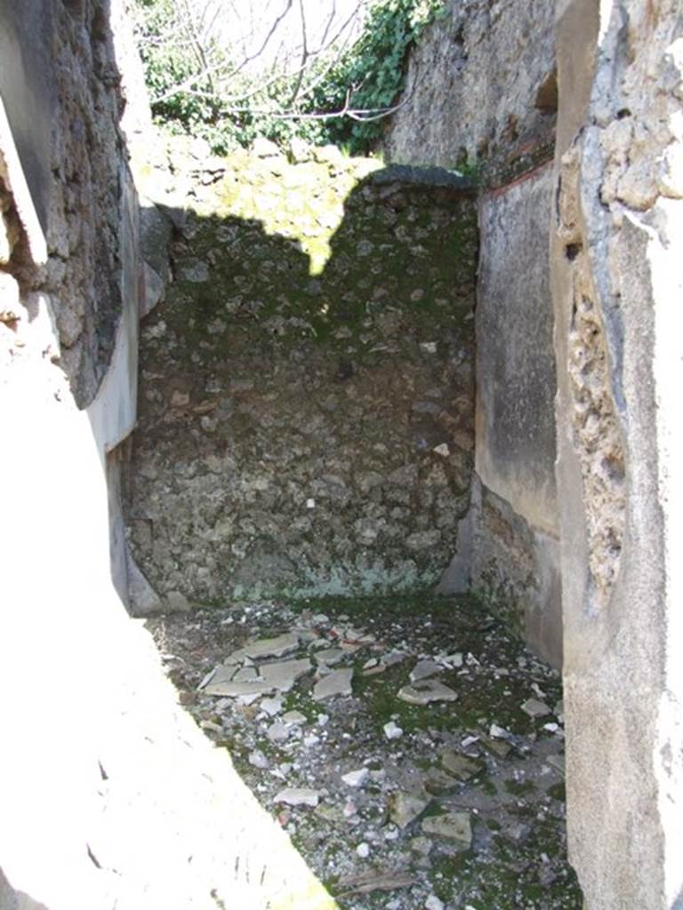 V.4.c Pompeii. March 2009.  Room H, looking east. Doorway to cubiculum on south side of tablinum. On the right of this doorway the painting of Mercury was discovered, on a large red panel. See the description on the photo entitled “Looking east across north side of atrium, room B” in Part 1. According to Sogliano, the doorway had a threshold of lava, and showed the remains of wood and raw plaster in the doorjambs. The room was divided into two parts. The rear part destined to contain the bed, which had its recess in the north wall, with the attic floor above rather low, so as to be almost an alcove.
The front part of the room had a higher ceiling. The decoration had a white background, separated into panels, with the base of the wall painted black. In the panels, flying animals could be seen, i.e. on the rear east wall two parrots with long ribbon between the beak and feet. On each of the two side walls were two swans and a flying stag, and on the wall at the entrance a ram. The floor was of cocciopesto. At the top of the south wall were the remains of a window and at a distance from it a rectangular niche that belonged to the room above.
Found on 15th March 1902 gathered together in the upper part of a room near the tablinum, a bronze statuette of Hercules with club and the apple of the Hesperides, together with the other objects described in NdS, page 213. See Notizie degli Scavi, 1905, (p.134).

