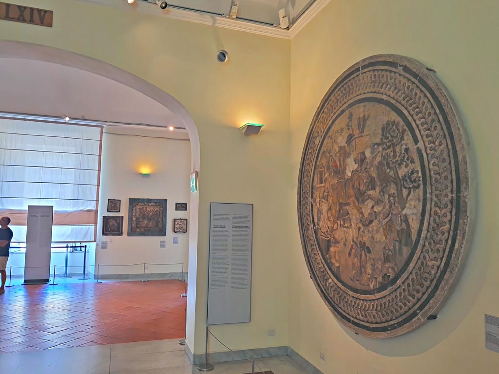 VI.9.5 Pompeii. September 2024. 
Looking across room in Naples Archaeological Museum with mosaic from triclinium 27, on right. Photo courtesy of Giuseppe Ciaramella.
