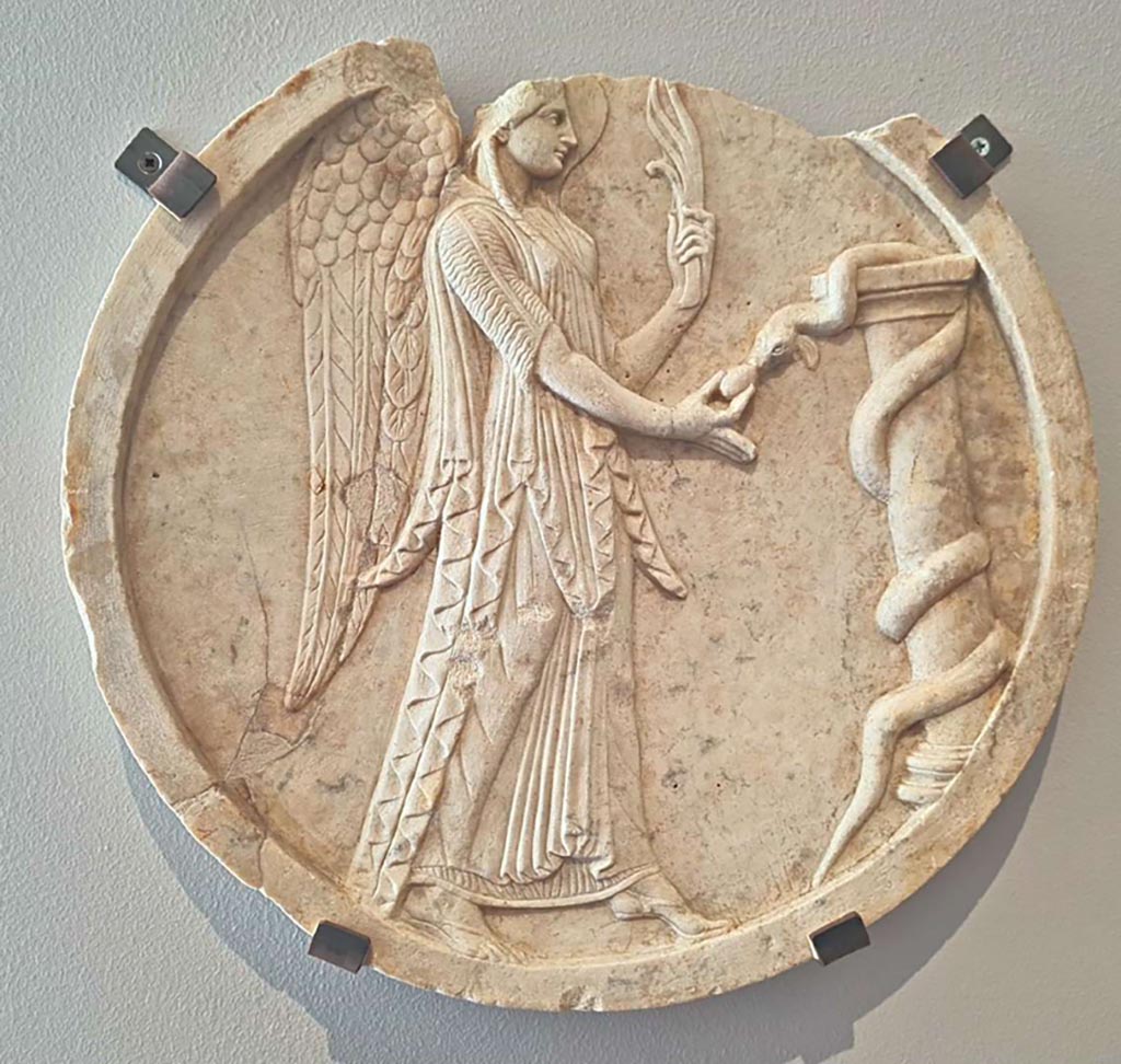 VII.4.59 Pompeii. October 2023. Peristyle o, double sided oscillum (side A) with winged Victoria.
Marble decorative hanging relief (oscilla) showing a winged Victory, inv. 6552. Photo courtesy of Giuseppe Ciaramella. 
On display in “L’altra MANN” exhibition, October 2023, at Naples Archaeological Museum.
