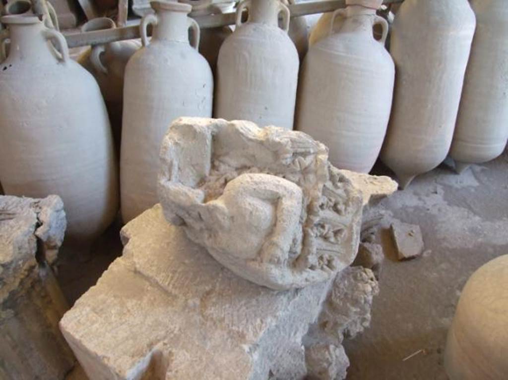 VII.4.59 Pompeii. December 2006. Remains of a capital in storage in the Forum Granary store VII.7.29. According to Spano, this damaged capital of Nocera tufa stone was found lying abandoned in a room of VII.4.59. When found, only half of each side was preserved, the left half of the front face and the right half of the side face. The above photo shows the side that would have been pointing into the fauces. He suggested it may have been the capital from the right side of the entrance of the House of Ariadne. See Notizie degli Scavi di Antichità, 1910, p.280 and p.282, fig. 12.