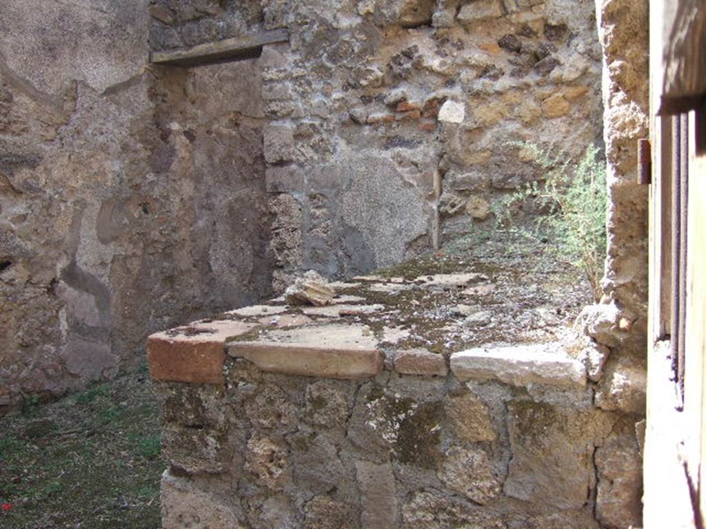 VII.7.5/14 Pompeii. September 2005. 
Looking west from entrance doorway at VII.7.14, along north wall and hearth or bench in kitchen area (s).

