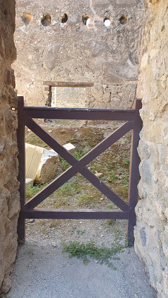 VII.9.3 Pompeii. August 2021. Looking east through doorway in south-east corner.
Foto Annette Haug, ERC Grant 681269 DÉCOR.
According to Fiorelli –
“A small door in the aedicule to the right of the atrium gave entrance to some adjoining rooms, communicating with those of the adjoining temple, and with an exit into the same “blind alley”.
(Una porticina che trovasi nell’edicola a destra dell’Atrio, dava adito ad alcune celle annesse, comunicanti con quelle del tempio adiacente, e con uscita nello stesso angiporto.)
See Pappalardo, U., 2001. La Descrizione di Pompei per Giuseppe Fiorelli (1875). Napoli: Massa Editore. (p.104-105).



