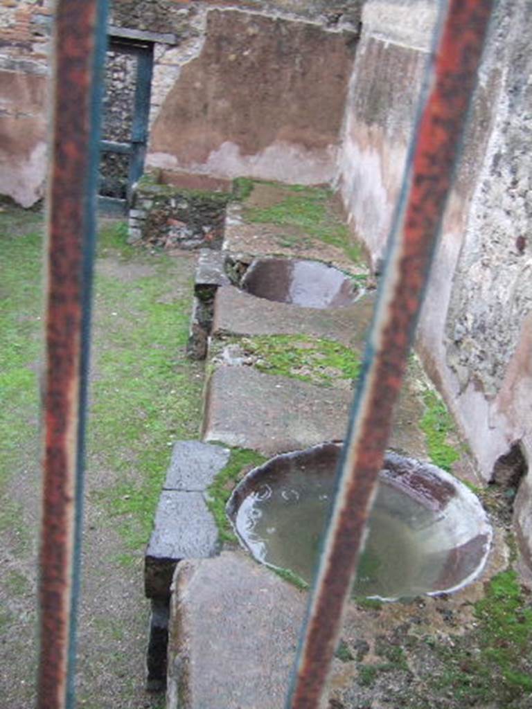 VII.12.17 Pompeii.  December 2005.  South side.  View from VII.12.21 of two round water basins in podium.