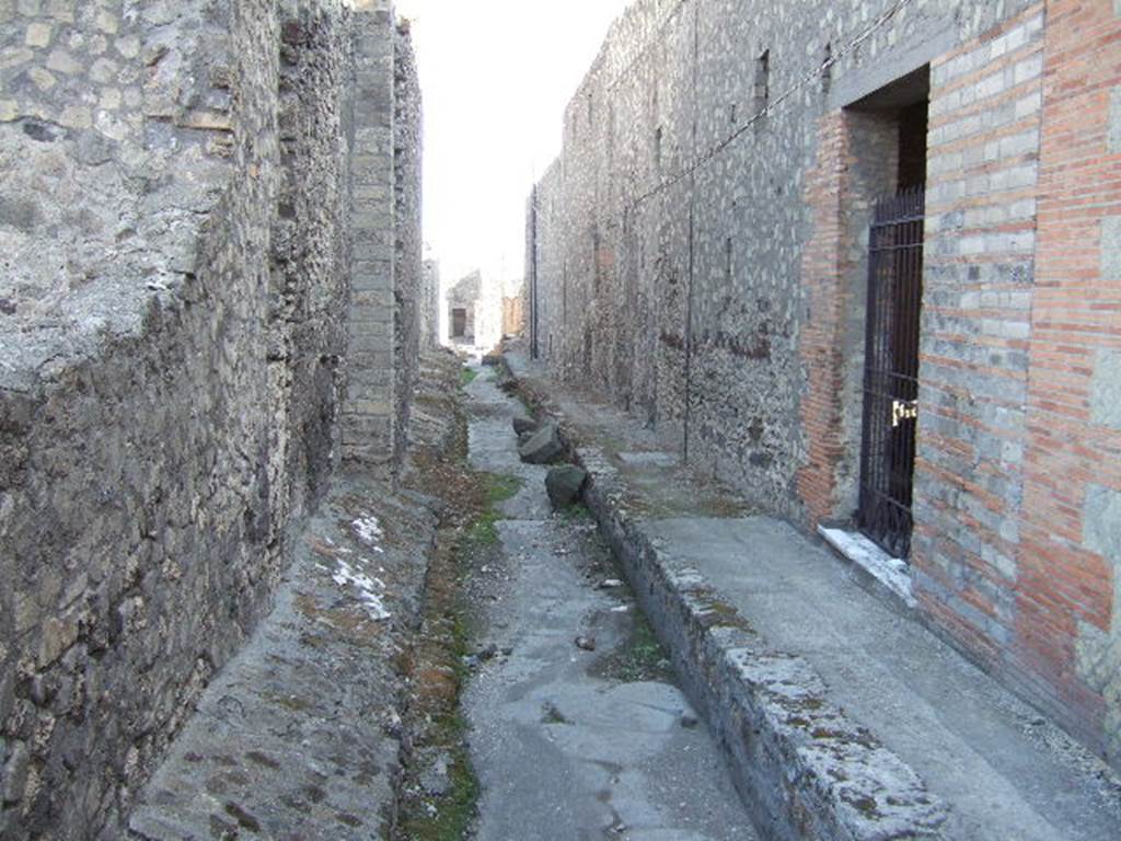 VII.6 Pompeii. September 2005. Vicolo del Farmacista, looking south. VII.16.21 on right. According to Garcia y Garcia, in 1943 the internal unexcavated area between VII.16. A and B (20 and 21) along the Vicolo del Farmacista was hit by a bomb. It fell on the soil not yet excavated and demolished the perimeter wall for a length of 4m x 3m and a part of the escarpment in two areas for 8 metres. 
See Garcia y Garcia, L., 2006. Danni di guerra a Pompei. Rome: LErma di Bretschneider. (p.137)

