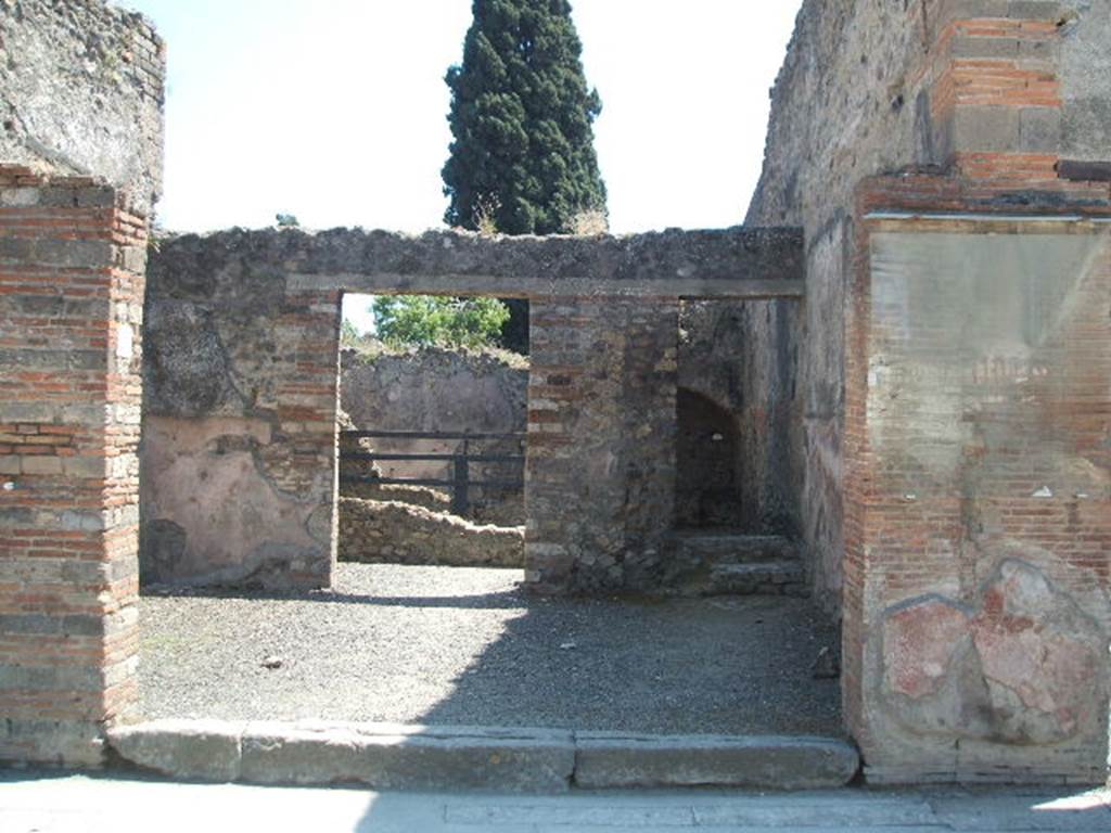 VIII.4.7 Pompeii. Shop and backroom, with VIII.4.9 in background.  May 2005.  For graffiti found on pilaster on right of doorway, see VIII.4.6. 
This included the one painted in red greek lettering, which was removed to the Naples Archaeological Museum.   Inventory number 4717. (Ruesch 1206).  This showed the shop’s owner to be under the protection of Hercules. [CIL IV 733]  Varone and Stefani include a photograph of the greek graffito.  See Varone, A. and Stefani, G., 2009. Titulorum Pictorum Pompeianorum, Rome: L’erma di Bretschneider, (p. 366)
Pappalardo shows the actual Fiorelli writings in greek.
See Pappalardo, U., 2001. La Descrizione di Pompei per Giuseppe Fiorelli (1875). Napoli: Massa Editore. (p.128)

