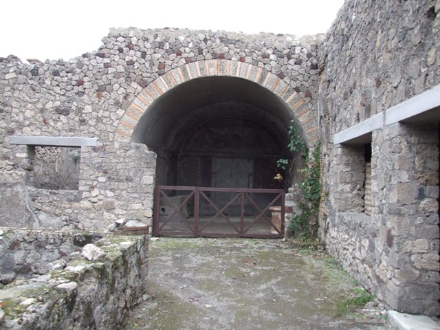 IX.2.10 Pompeii. December 2007.  Looking east along the walkway on the south side of the peristyle, towards the vaulted room or tablinum. On the right is the window and doorway of a cubiculum, with red zoccolo and panelled middle zone to the walls, but now all faded. 
On the left is the window of a triclinium, described by Fiorelli as an oecus.
See Fiorelli, G, (1875),  Descrizione di Pompei, (p.380)

