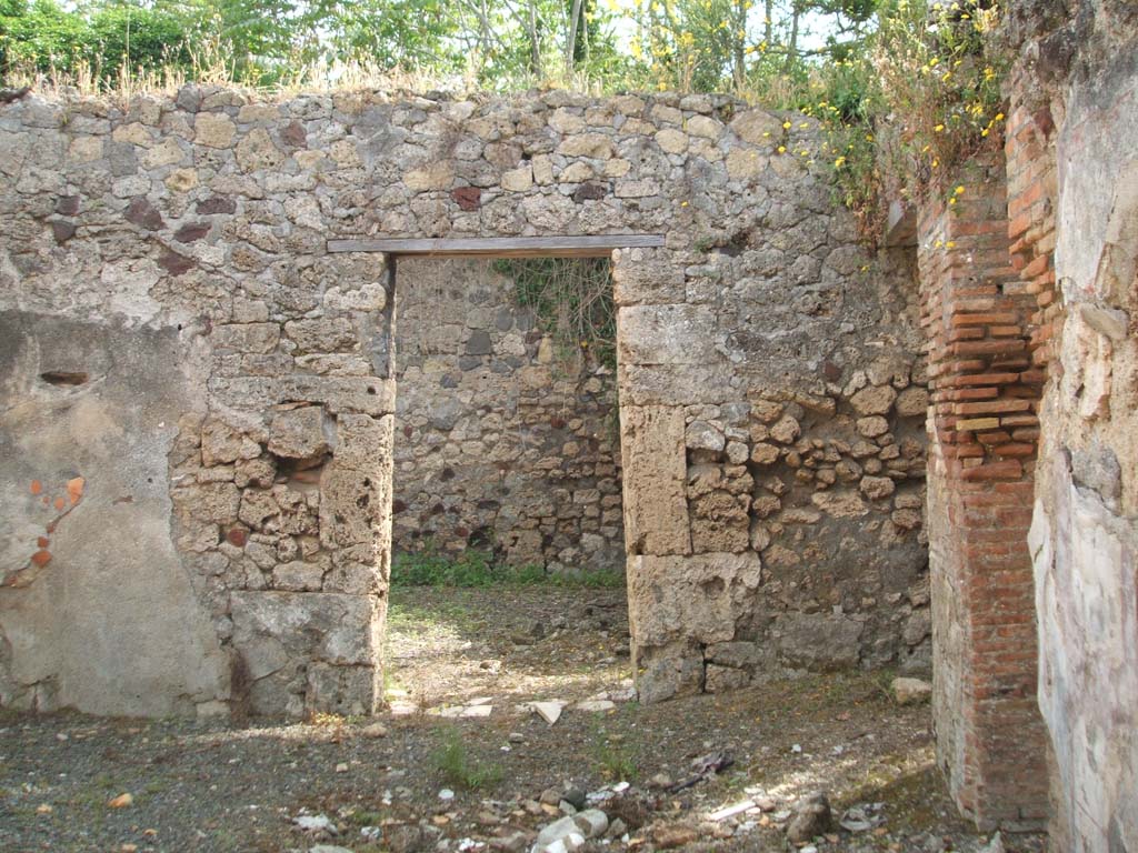 IX.7.19 Pompeii. May 2005. Looking east to doorway to room g, triclinium in rear wall of atrium, in centre of photo. 
The threshold in the doorway of the triclinium was made of marble.
