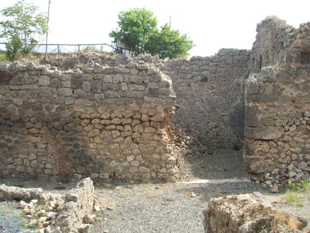 IX.7.21 Pompeii. May 2005. Looking east across atrium to doorway to room, according to Mau possibly used as a dining room.
Leaning against the east wall of the atrium would have been the stairs leading to the rooms on the upper floor, above the north-east corner of the atrium.
Under the stairs in the north-east corner would have been a storage area or cupboard.
In the lower left corner of the photo, can be seen the remains of the pluteus from around the impluvium.
The four brick pilasters of the Corinthian atrium have now vanished.
See Mau in Bullettino dell’Instituto di Corrispondenza Archeologica (DAIR), 1882, (p.184)

