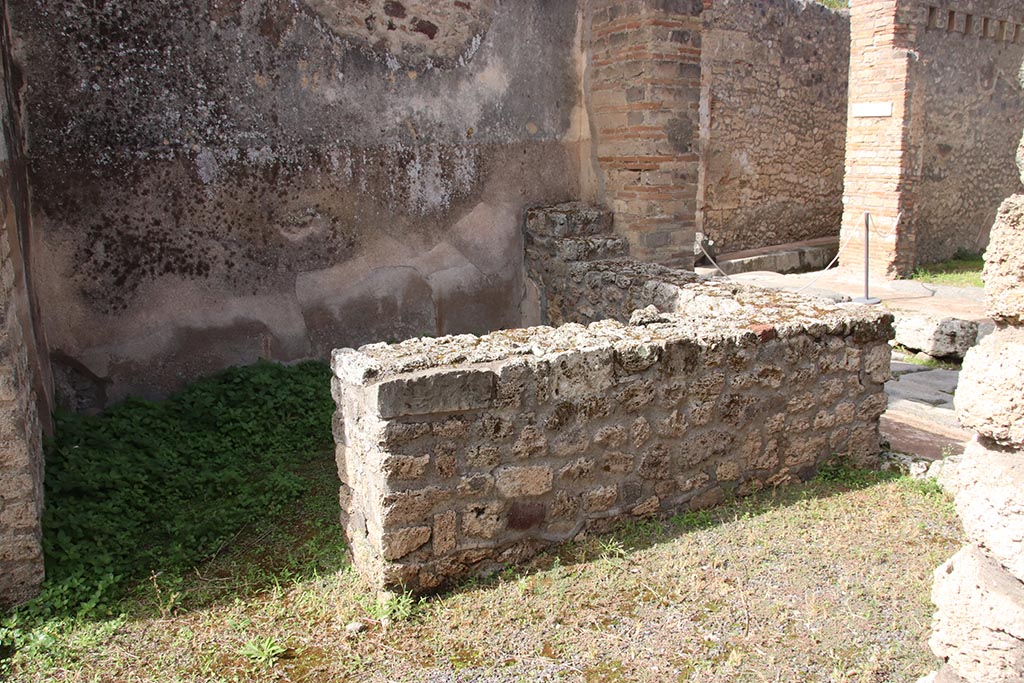 IX.7.21/22 Pompeii. May 2003. Hearth in north-west corner of atrium of IX.7.21. 
Above the hearth in the west wall is a panel of white stucco. In the panel is a square niche.
Photo courtesy of Nicolas Monteix.
