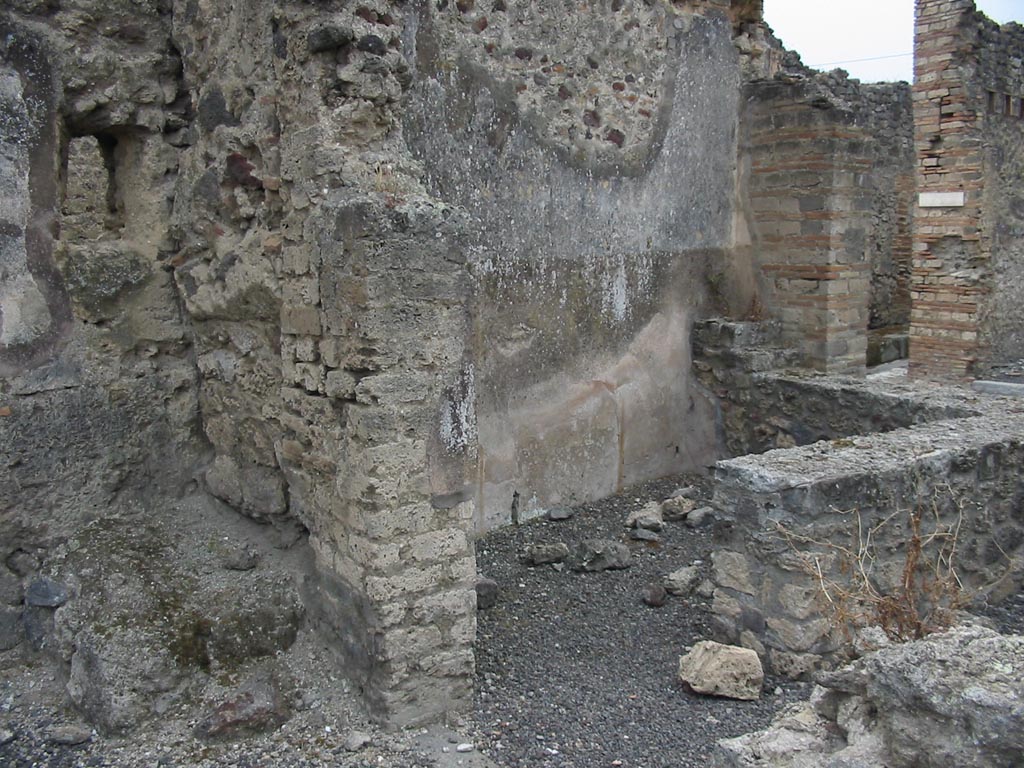 IX.7.21/22 Pompeii. 1937. Lararium in north-west corner of atrium of IX.7.21.
According to Boyce, in the north-west corner of the atrium was the hearth.
Above the hearth in the west wall was a panel of white stucco. In the panel was a square niche.
Its edges were outlined in red against the white background and below it was a cornice.
On the reddish coloured back wall of the niche was painted a white object, which Mau was unable to identify.
He did state that it was not a phallus.
Below the niche was a painted garland of red and green leaves and below it a burning altar with a pine-cone.
On either side of the altar was a yellow serpent.
The serpent on the left had a red crest and beard, the head of the other was damaged.
See Boyce G. K., 1937. Corpus of the Lararia of Pompeii. Rome: MAAR 14.  (p.88, no.441, and Pl.4, 4)
According to Giacobello, the painting is no longer conserved.
See Giacobello, F., 2008. Larari Pompeiani: Iconografia e culto dei Lari in ambito domestico. Milano: LED Edizioni. (p.250)
See Mau in Bullettino dellInstituto di Corrispondenza Archeologica (DAIR), 1882, (p.195)
