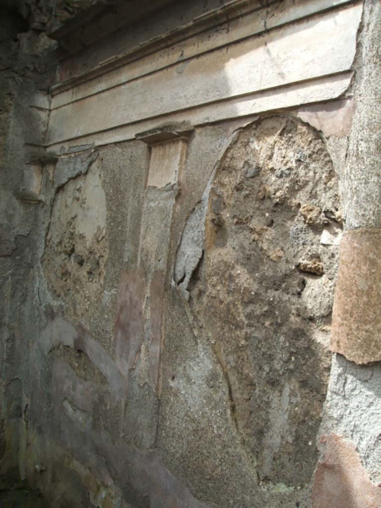 IX.7.25 Pompeii. May 2005. West wall of garden area “u”, with remains of moulded cornice. 
According to Jashemski, Mau had said on the south garden wall (not photographed here), to the right (west) of the door leading to a back room, there was a painting of a kind of pavilion.
This was formed by four columns in which stood a large crater fountain (79cm high).
It was decorated with plant and animal motifs in high relief.
The jetting water fell back into the crater from a height of about 20cm.
Fortunately, Tatiana Warscher had photographed the now-destroyed detail.
She said this was found “at the base of the middle of the garden wall”.
Nothing remains today.
See Jashemski, W. F., 1993. The Gardens of Pompeii, Volume II: Appendices. New York: Caratzas. (No.96 on p.366).
The Tatiana Warscher photograph can be seen on page 367, fig. 430 of the same book.
Jashemski also included a mosaic fountain at IX.7.25, that we have included in IX.7.20.
See Jashemski, W. F., 1993. The Gardens of Pompeii, Volume II: Appendices. New York: Caratzas. (p.242).
See Boyce G. K., 1937. Corpus of the Lararia of Pompeii. Rome: MAAR 14. (p.89, no.446, he gives the location as IX.7.?) 
