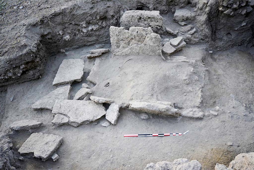 The collapsed slabs of burial SP30055 (HGE31A) being excavated. Taken from the east. 
Photo  B. Lemaire, EFR/CNRS. 
Burial SP30055, shows elements of the fractured and fallen wall slabs (Fig. 24). 
It was a box burial consisting of four monolithic slabs of Sarno limestone placed in the field, delimiting a space in which the deceased and the offerings were placed. 
The levels in place that have come down to us allow us to put forward the hypothesis that the burial is installed in the substratum, most probably with the digging of a pit whose limits are represented by the blocks forming the burial. 
The slabs on the short sides are enclosed by those on the long sides, forming a box and defining a rectangular structure of 2.25 m by 1.40 m (maximum), oriented north-east/south-west.
The north-western wall, which is better preserved (31.94 m s.l.m.), makes it possible to restore the height and thus the internal space of the tomb: 1.94 m by 0.98 m, for a height of 1.08 m.
(See CEFR 1581 and below) Para 42, Fig. 24.

Les dalles effondres de la spulture SP30055 en cours de fouille. Pris de lest. 
Photo  B. Lemaire, EFR/CNRS. 
La spulture SP30055, prsente des lments des dalles des parois fractures et tombes au sol (fig. 24). 
Il sagissait dune spulture  caisse matrialise par quatre dalles monolithes en calcaire du Sarno poses de champ, dlimitant un espace dans lequel sont installs le dfunt et les offrandes. 
Les niveaux en place qui nous sont parvenus permettent davancer lhypothse que la spulture est installe dans le substrat, trs probablement avec le creusement dune fosse dont les limites sont reprsentes par les blocs formant la spulture. 
Les dalles des petits cts sont enserres par celles des grands cts, formant un coffre et dfinissant une structure rectangulaire de 2,25 m sur 1,40 m (au maximum), oriente nord-est/sud-ouest.
La paroi nord-ouest, mieux conserve (31,94 m s.l.m.), permet de restituer la hauteur et ainsi lespace interne de la tombe : 1,94 m sur 0,98 m, pour 1,08 m de hauteur.
(Voir CEFR 1581 et ci-dessous) Para. 42, Fig. 24.
