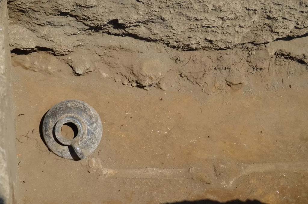 HGE32A Pompeii. June 2016. Tomb of a Samnite Man. The black painted jug next to the right foot of the deceased Samnite

La brocca a vernice nera accanto al piede destro del defunto sannita

Photograph  Parco Archeologico di Pompei.

