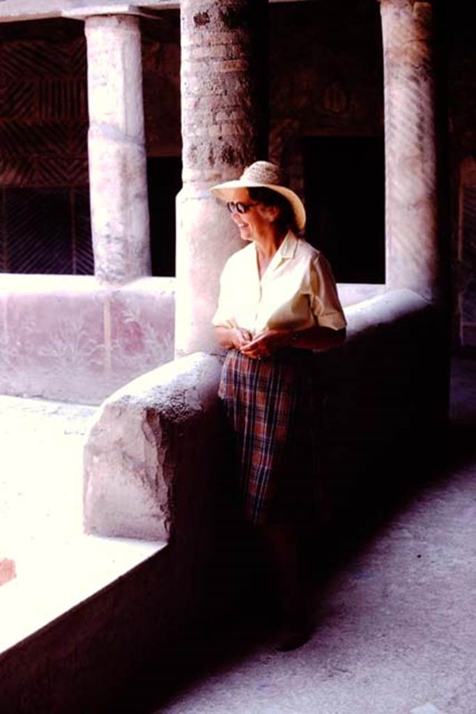 Oplontis, 1974. Room 32, Wilhelmina in the rustic peristyle. Looking south-east, the interior wall of the pluteus (low wall) can be seen painted with plants. Photo by Stanley A. Jashemski.   
Source: The Wilhelmina and Stanley A. Jashemski archive in the University of Maryland Library, Special Collections (See collection page) and made available under the Creative Commons Attribution-Non Commercial License v.4. See Licence and use details. J74f0621

